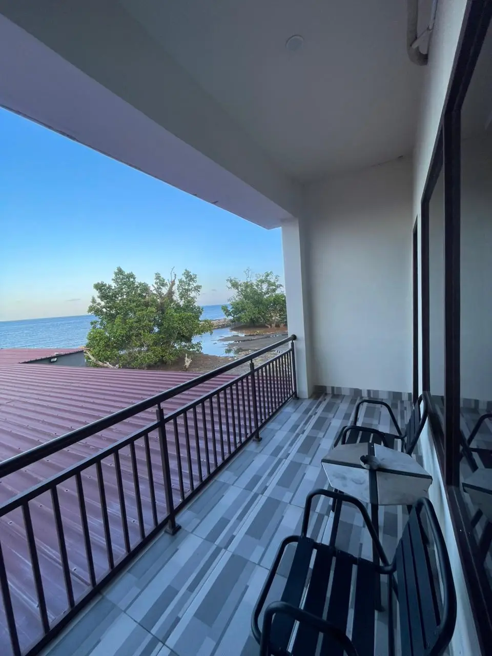 Private balcony of a Deluxe Room with outdoor chairs and ocean view.