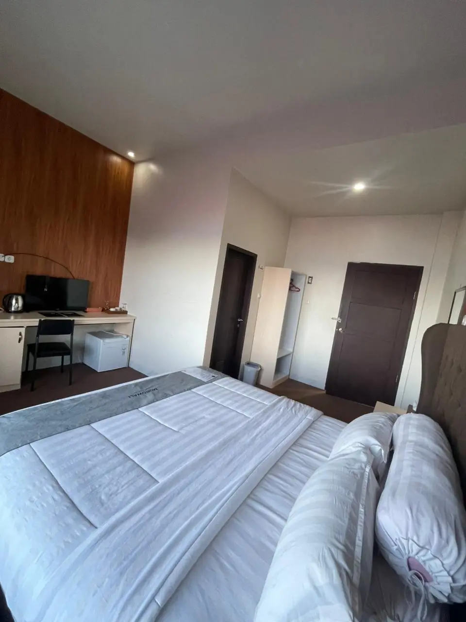 Modern deluxe hotel room with a large bed, workspace, and wooden accents.