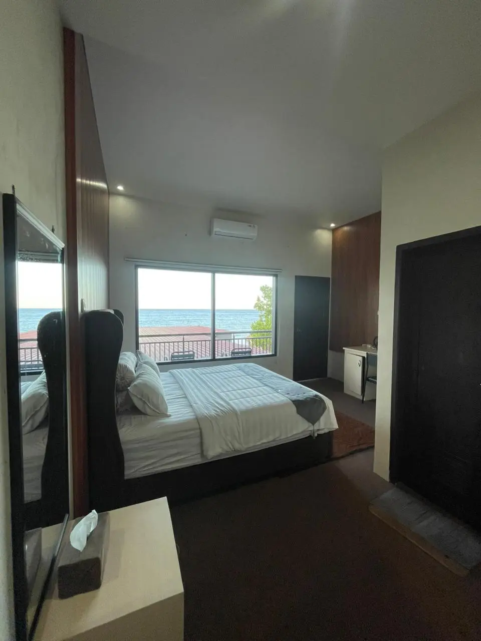 Deluxe hotel room with a large bed and a scenic ocean view through the window.