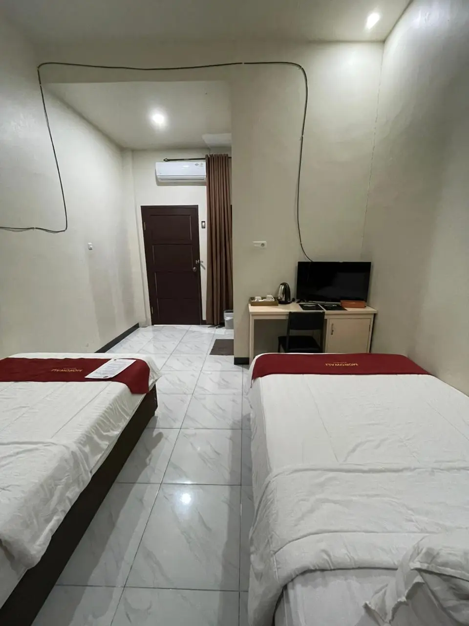 Kamar hotel tipe Standard Twin dengan dua tempat tidur single dan area meja kerja.