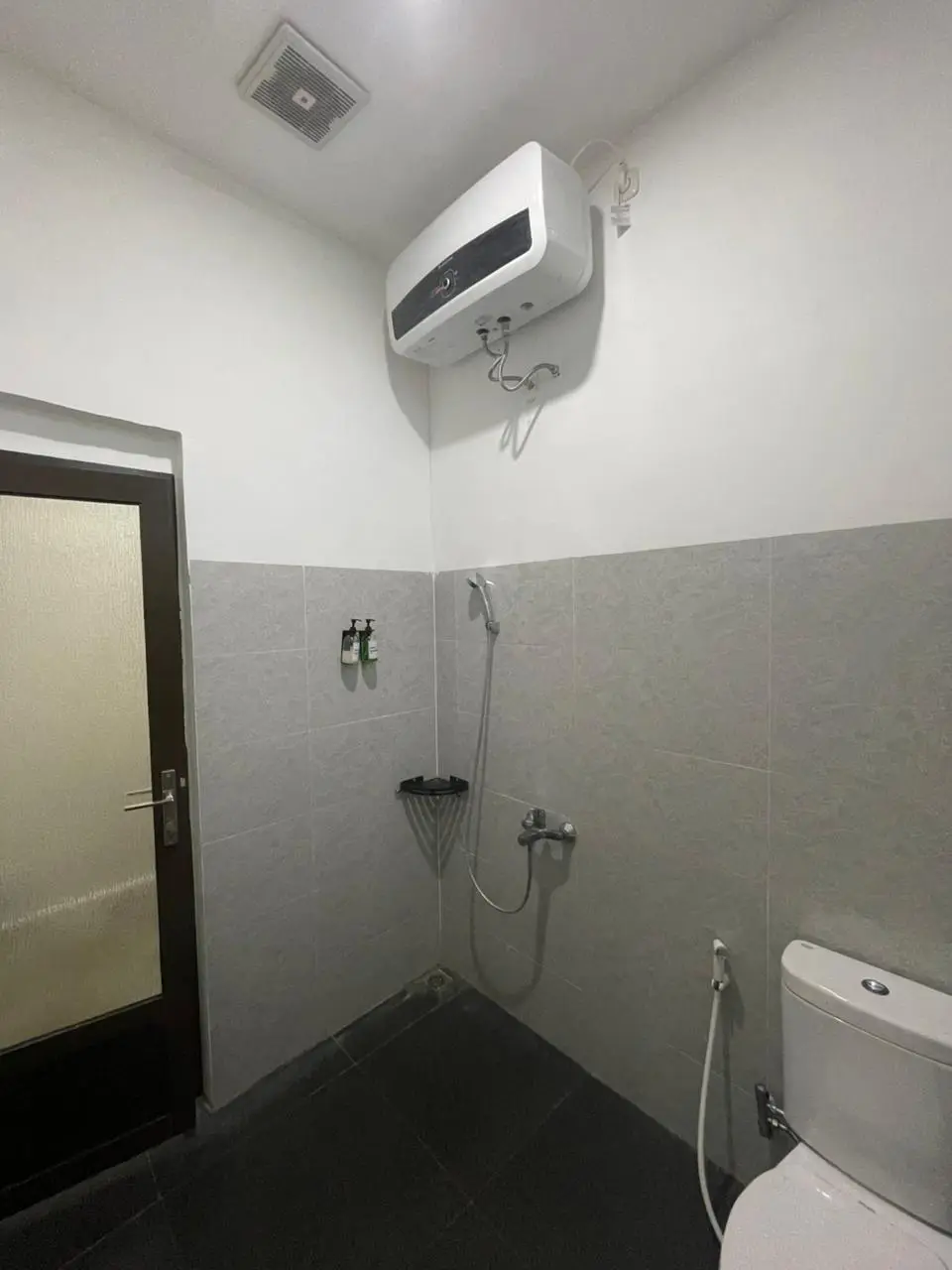 Modern bathroom interior in a Junior Suite Room featuring a toilet, shower, and water heater.