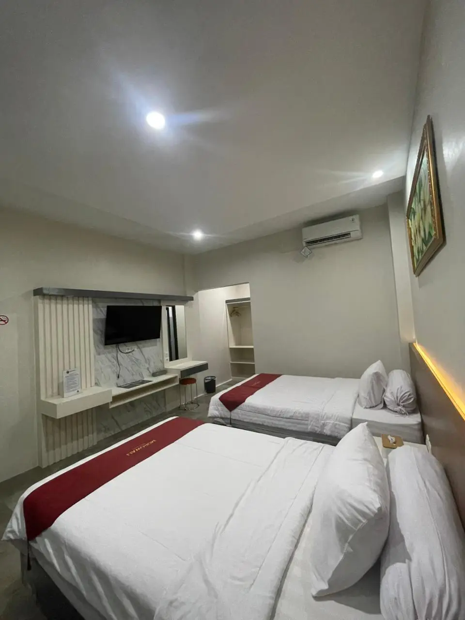 Modern Junior Suite Room with two double beds, a wall-mounted flat-screen TV, and clean white decor.