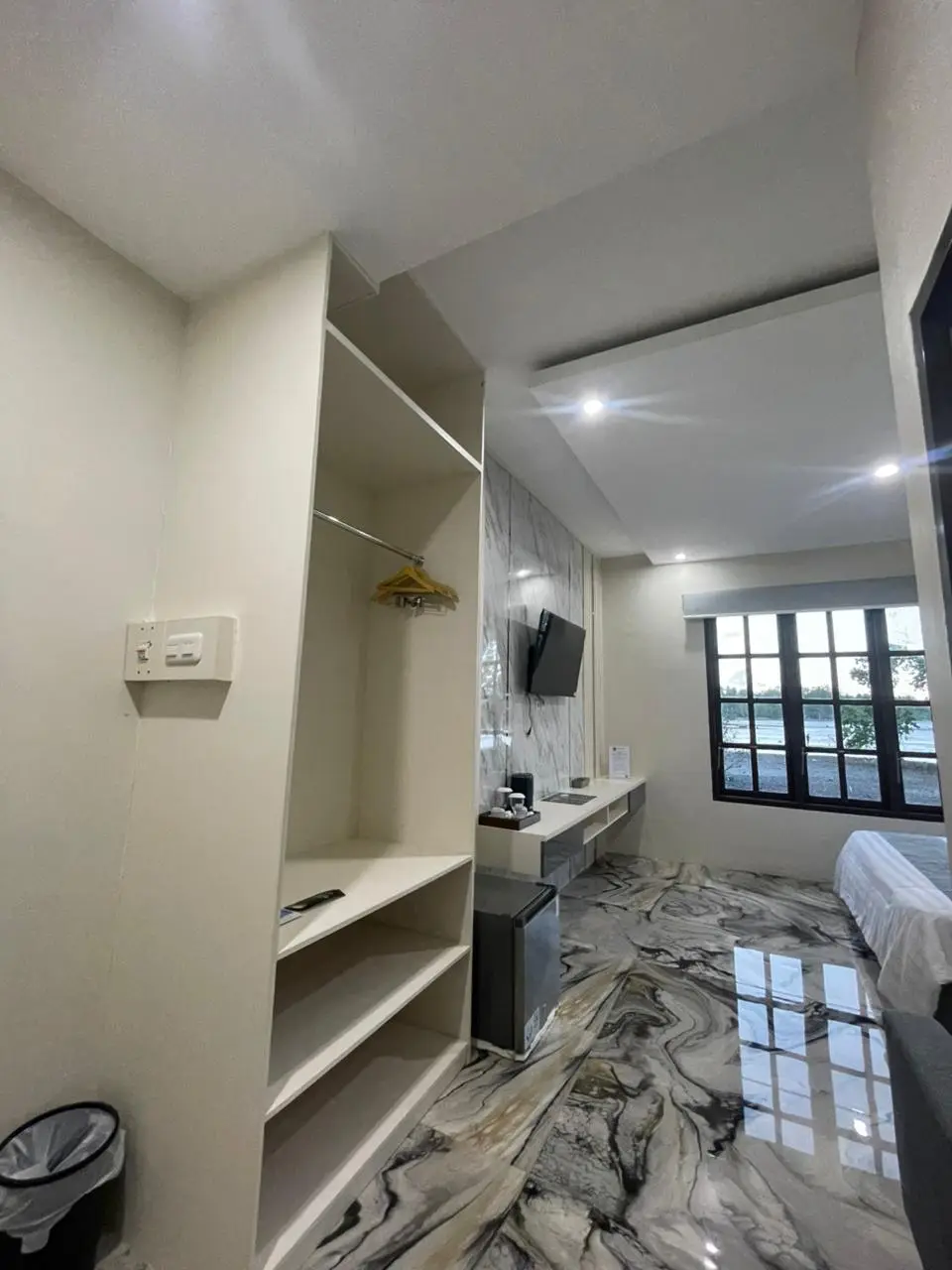 Modern suite room with an open closet, marble-patterned flooring, and wall-mounted TV.