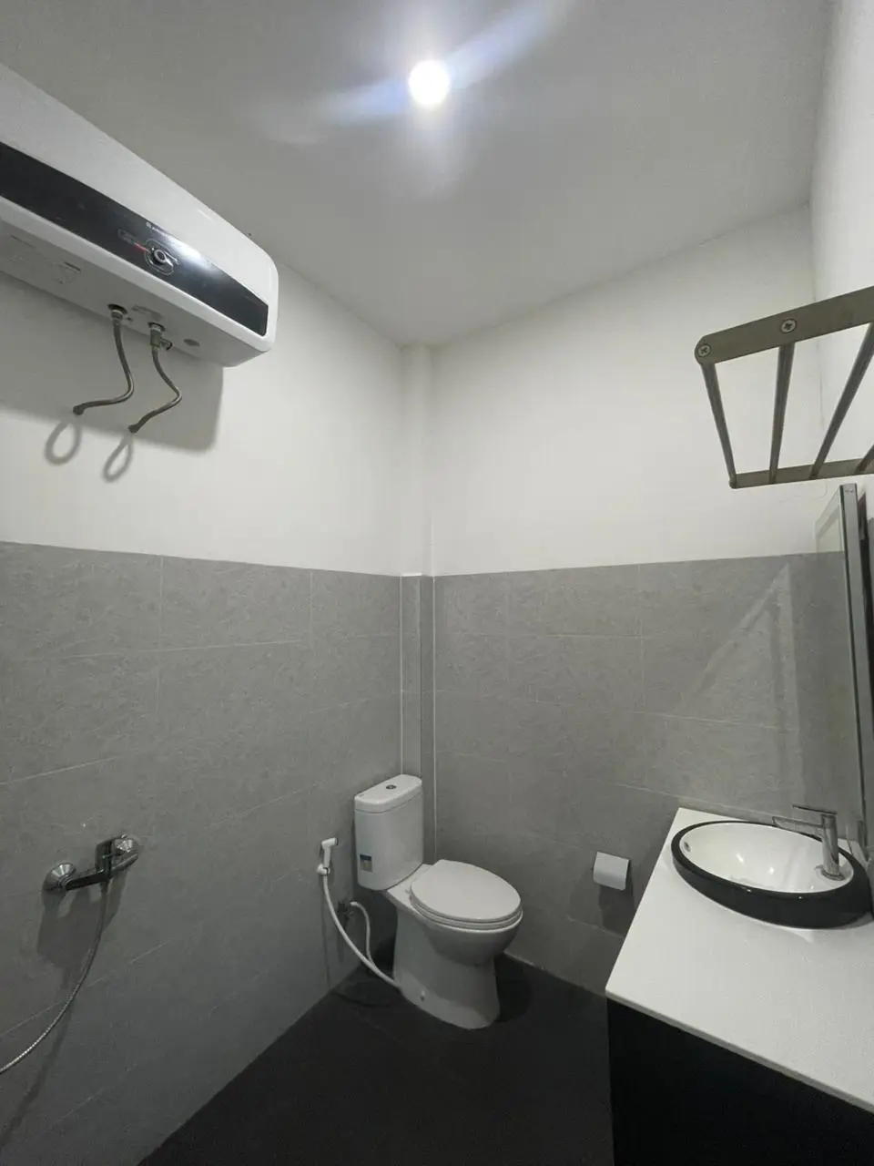 Interior kamar mandi modern Suite Room Ocean View yang dilengkapi ubin abu-abu dan perlengkapan keramik putih.