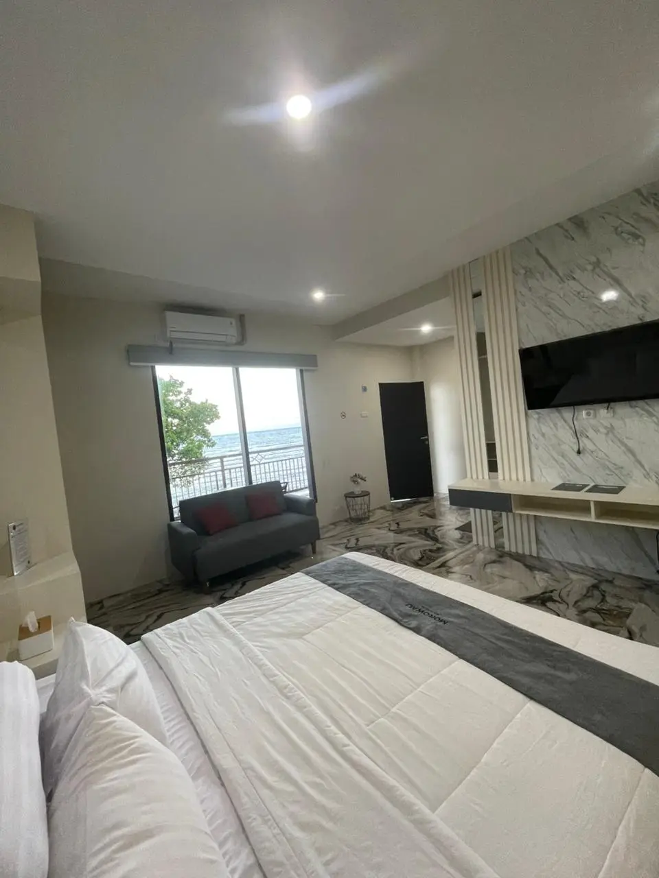 Kamar suite mewah dengan pemandangan laut yang dilengkapi lantai marmer, tempat tidur king-size, dan balkon pribadi.