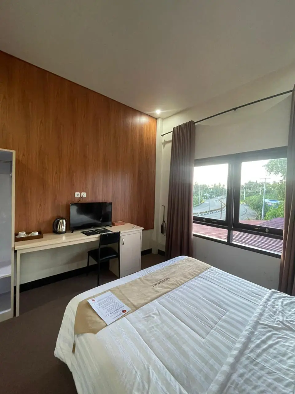 Kamar hotel superior double dengan dinding aksen kayu, meja kerja, dan jendela besar dengan pemandangan.