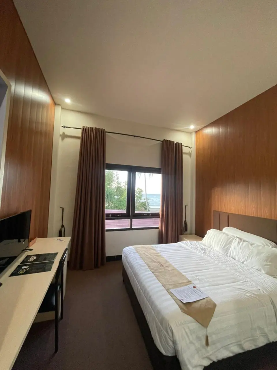 Kamar Superior Double dengan dinding panel kayu, tempat tidur besar, meja kerja, dan pemandangan jendela.