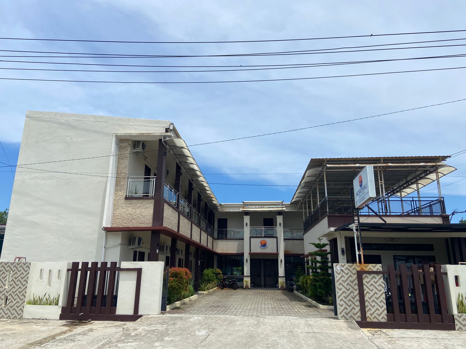 The main building exterior of Morowali Beach Hotel with a paved entrance and balconies under a clear sky