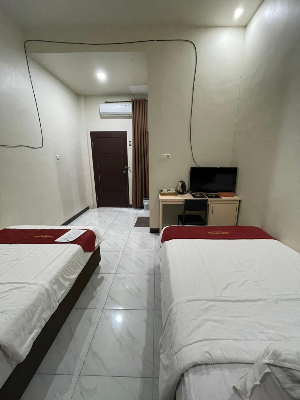 Kamar hotel tipe Standard Twin dengan dua tempat tidur single dan area meja kerja.