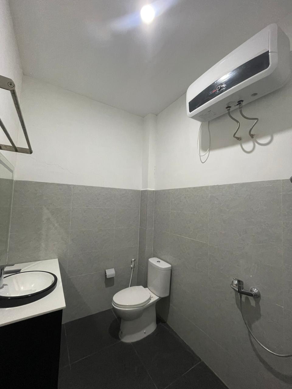 Kamar mandi yang fungsional dan bersih di kamar suite hotel dengan ubin abu-abu dan perlengkapan modern.