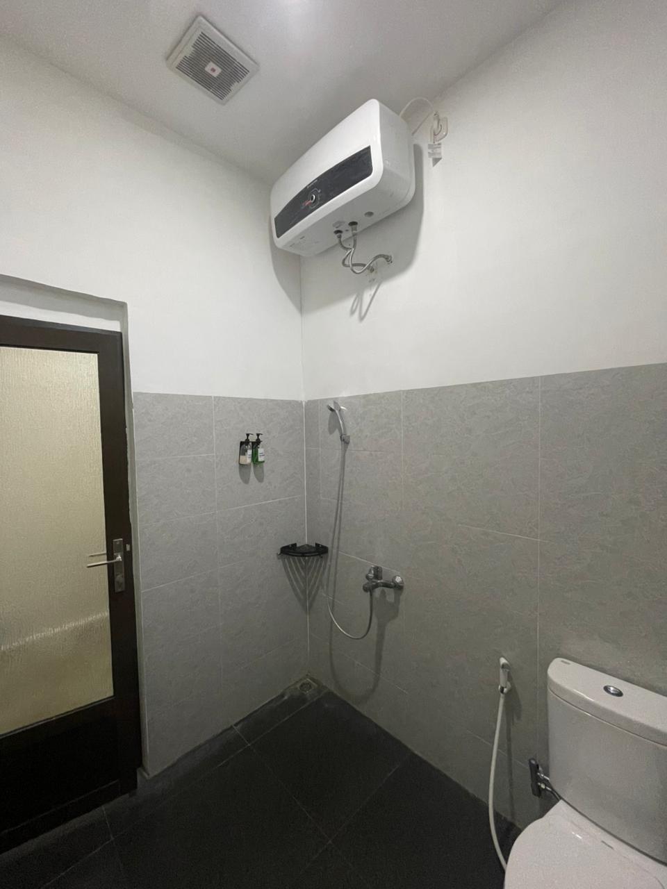 Interior kamar mandi modern di Junior Suite Room yang dilengkapi dengan toilet, shower, dan pemanas air.