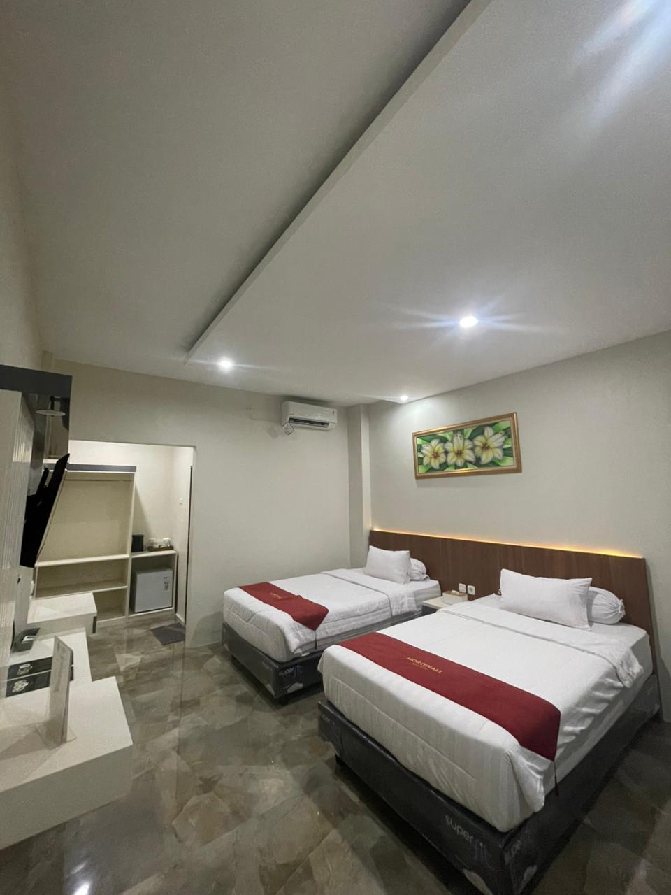 Kamar hotel tipe Junior Suite dengan dua tempat tidur, seprai putih, dan TV di dinding.