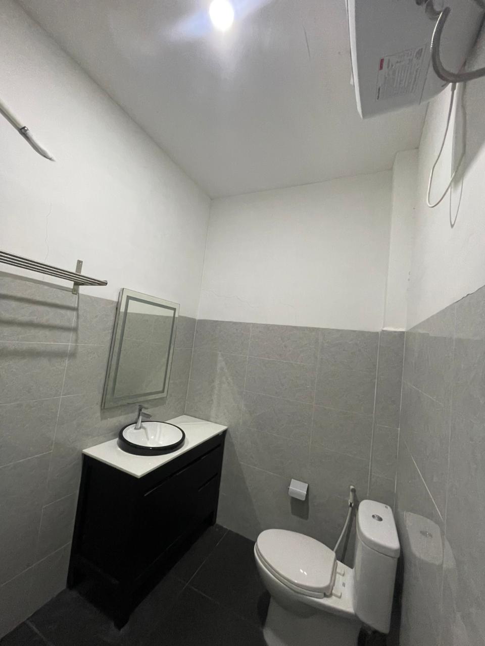 Kamar mandi modern dengan wastafel hitam dan toilet putih di kamar suite.