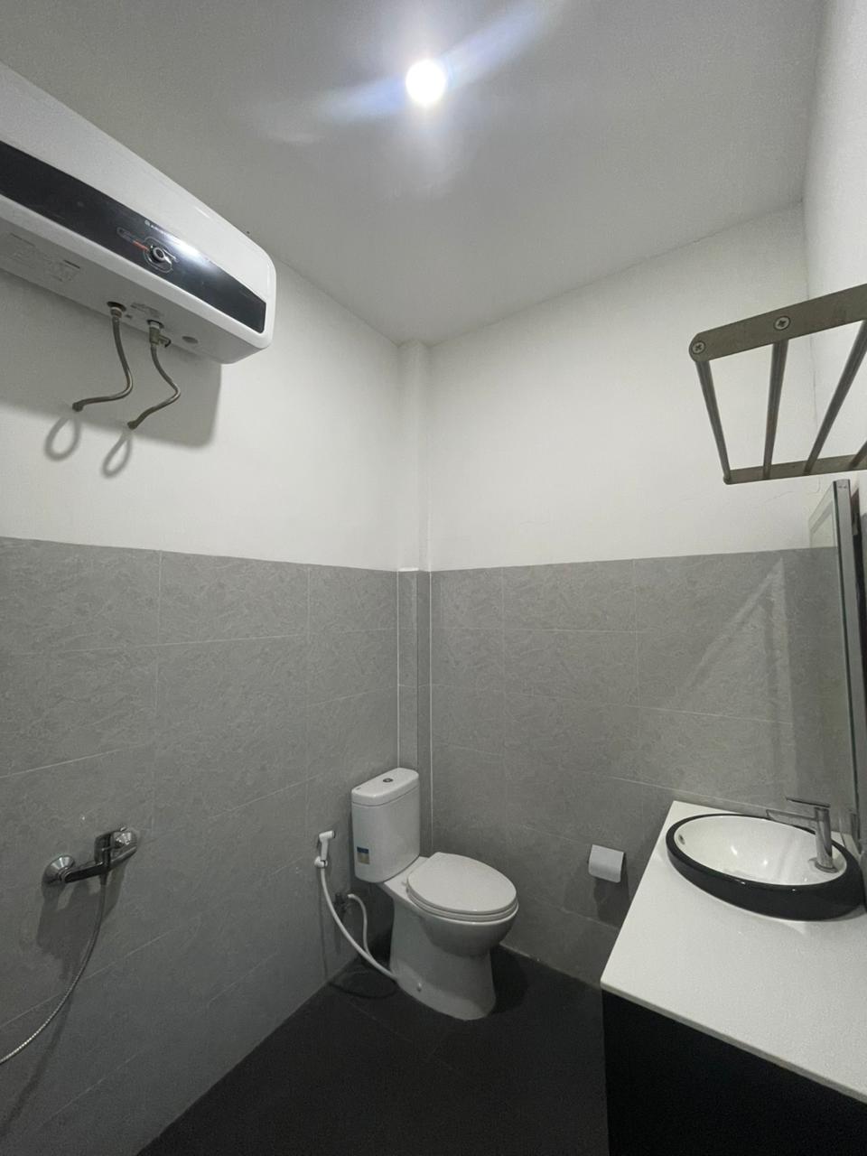 Interior kamar mandi modern Suite Room Ocean View yang dilengkapi ubin abu-abu dan perlengkapan keramik putih.