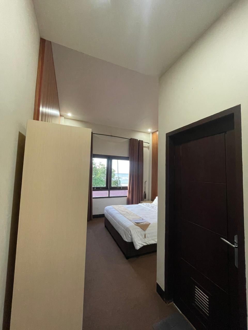 Kamar Superior Double dengan pemandangan laut, menampilkan tempat tidur ganda dan pencahayaan hangat.