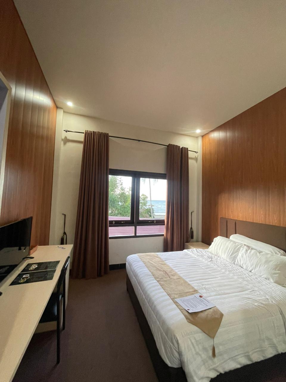 Kamar Superior Double dengan dinding panel kayu, tempat tidur besar, meja kerja, dan pemandangan jendela.