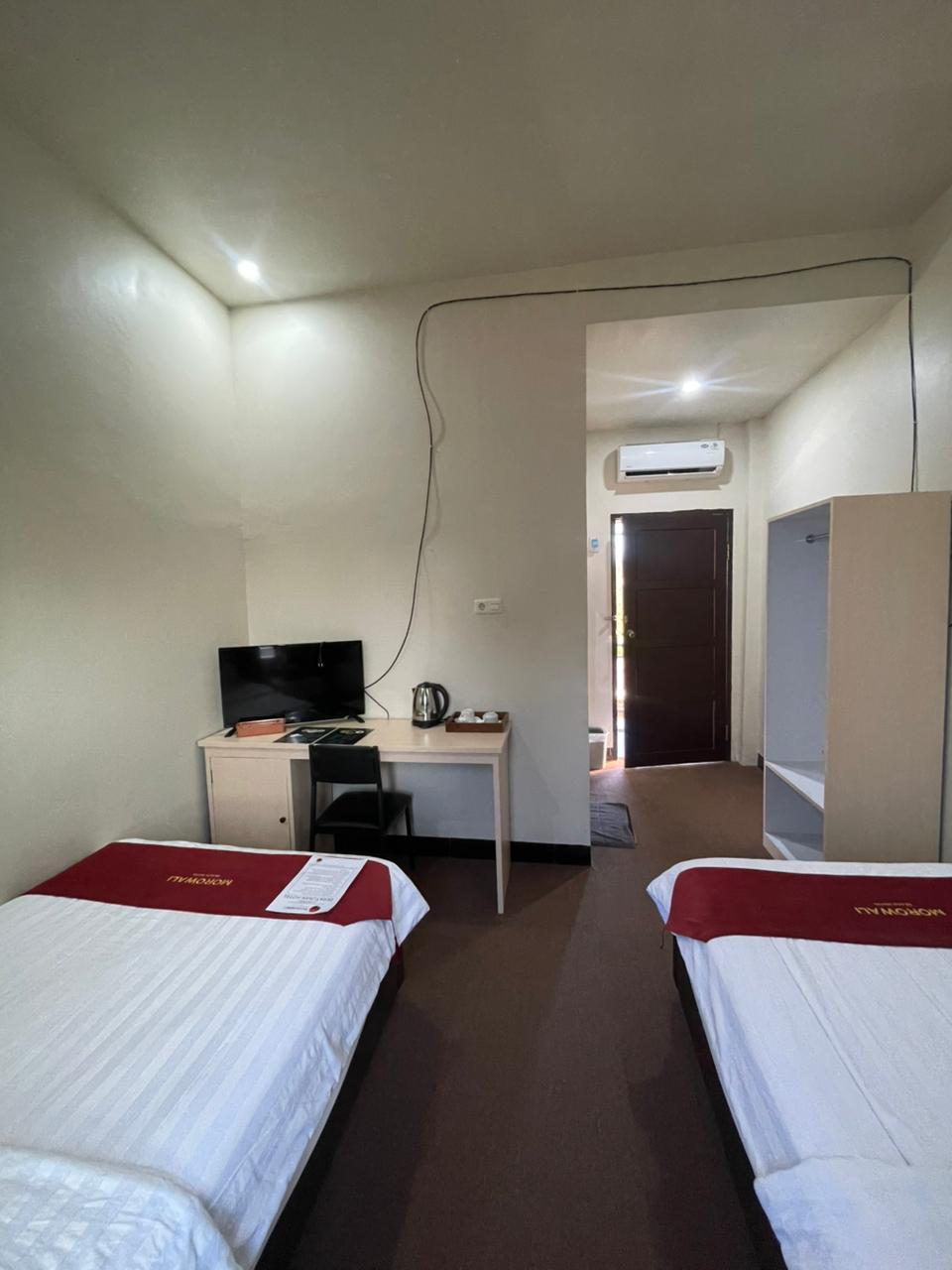 Kamar superior twin dengan dua tempat tidur single, area kerja dengan TV, dan lemari pakaian terbuka.